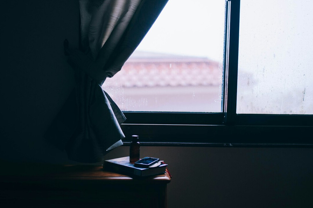 Laptop and notes on a desk by a window